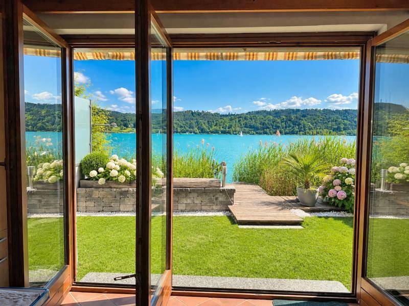 Heller Innenraum mit großen Glasfronten und Panoramablick auf den See und den Garten.