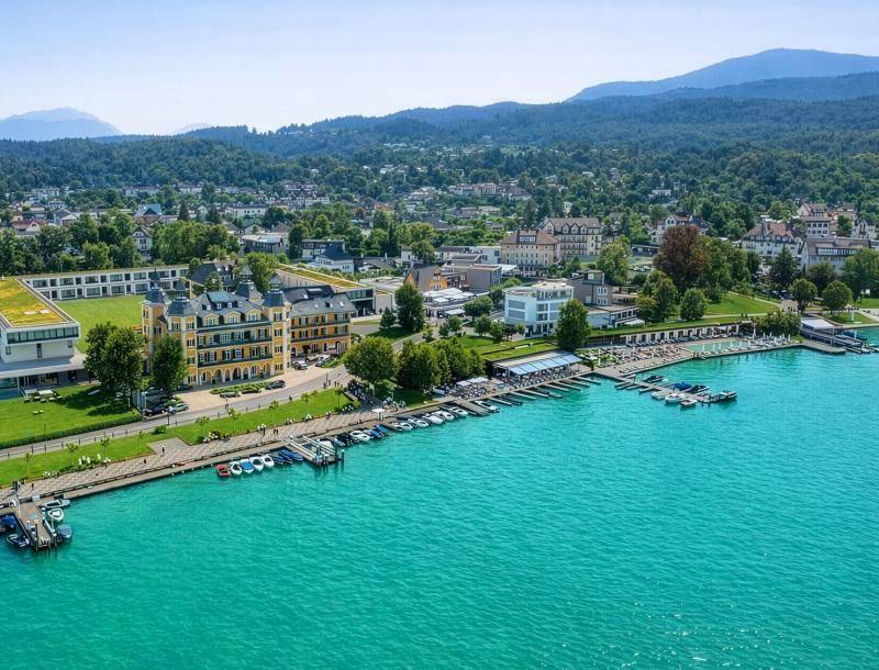 Malerische Luftaufnahme der Stadt am See mit grünen Hügeln und Gebäuden.
