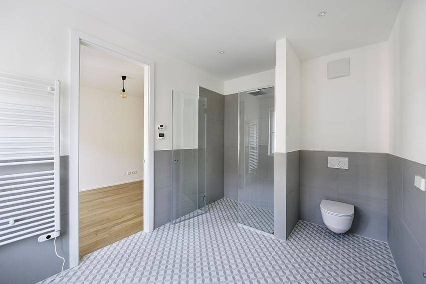 Modernes Badezimmer mit begehbarer Dusche, Wand-WC und stilvollen Fliesen.