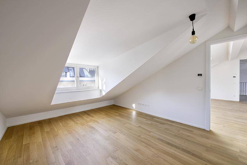 Helles Dachzimmer mit Holzboden, schräger Decke und weitem Ausblick.