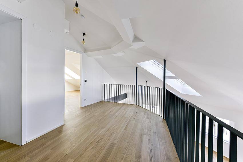 Heller Dachgeschossraum mit schrägen Decken, Dachfenstern und offener Galerie.