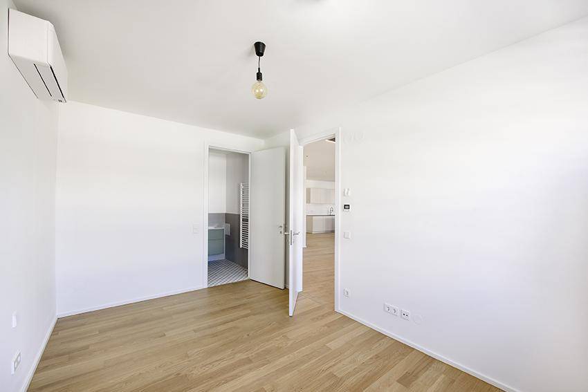 Helles Schlafzimmer mit Holzboden und Zugang zu einem modernen Badezimmer.
