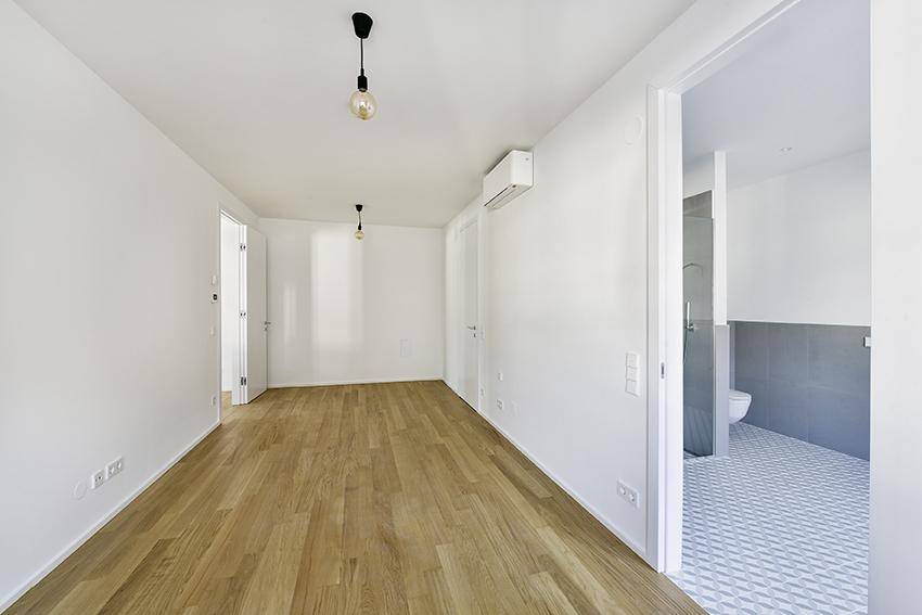 Helles Schlafzimmer mit Holzboden und direktem Zugang zu einem modernen Badezimmer.