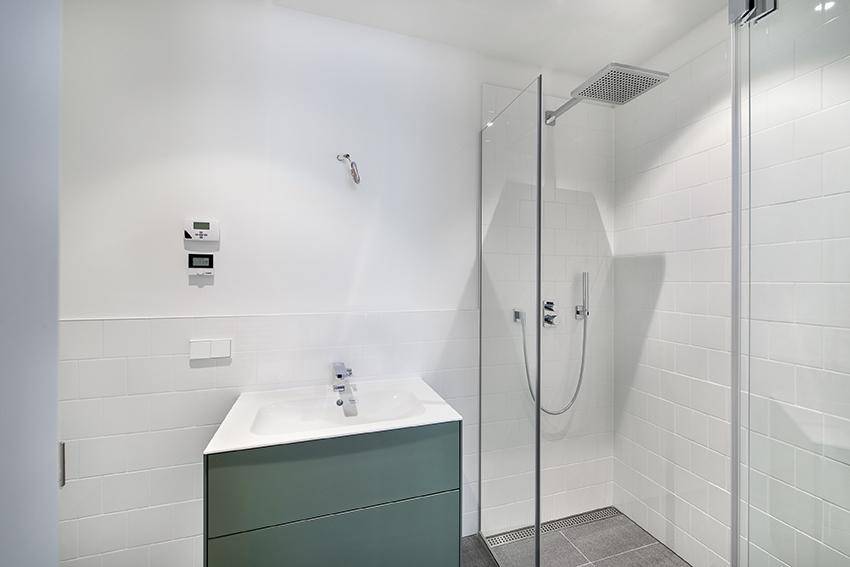 Modernes Badezimmer mit ebenerdiger Dusche, Einzelwaschbecken und weißen Fliesen.