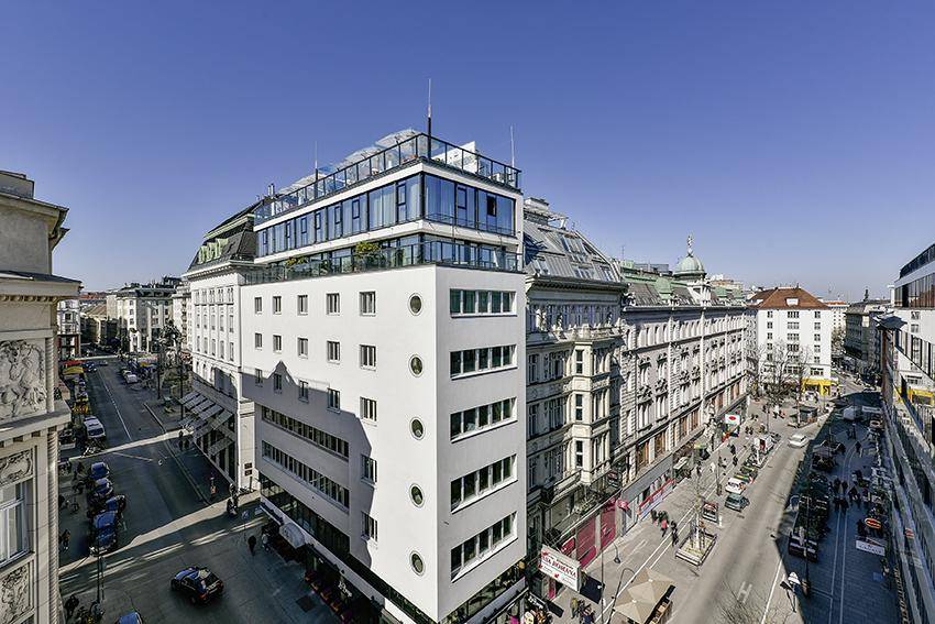 Luftaufnahme eines modernen Gebäudes in der Stadt mit umliegenden historischen Bauten.