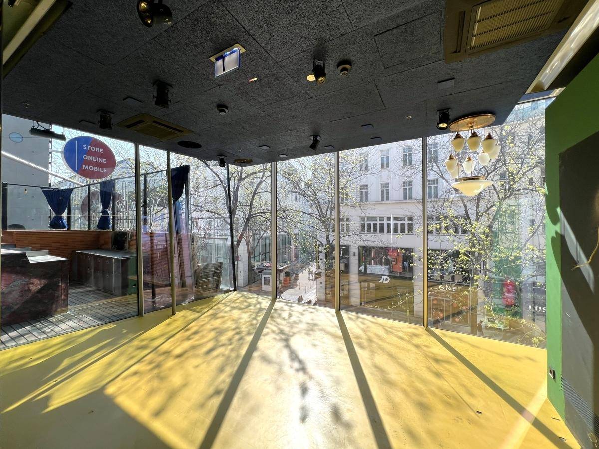Heller Gewerberaum mit großen Fensterfronten, gelbem Boden und Blick auf die belebte Straße.
