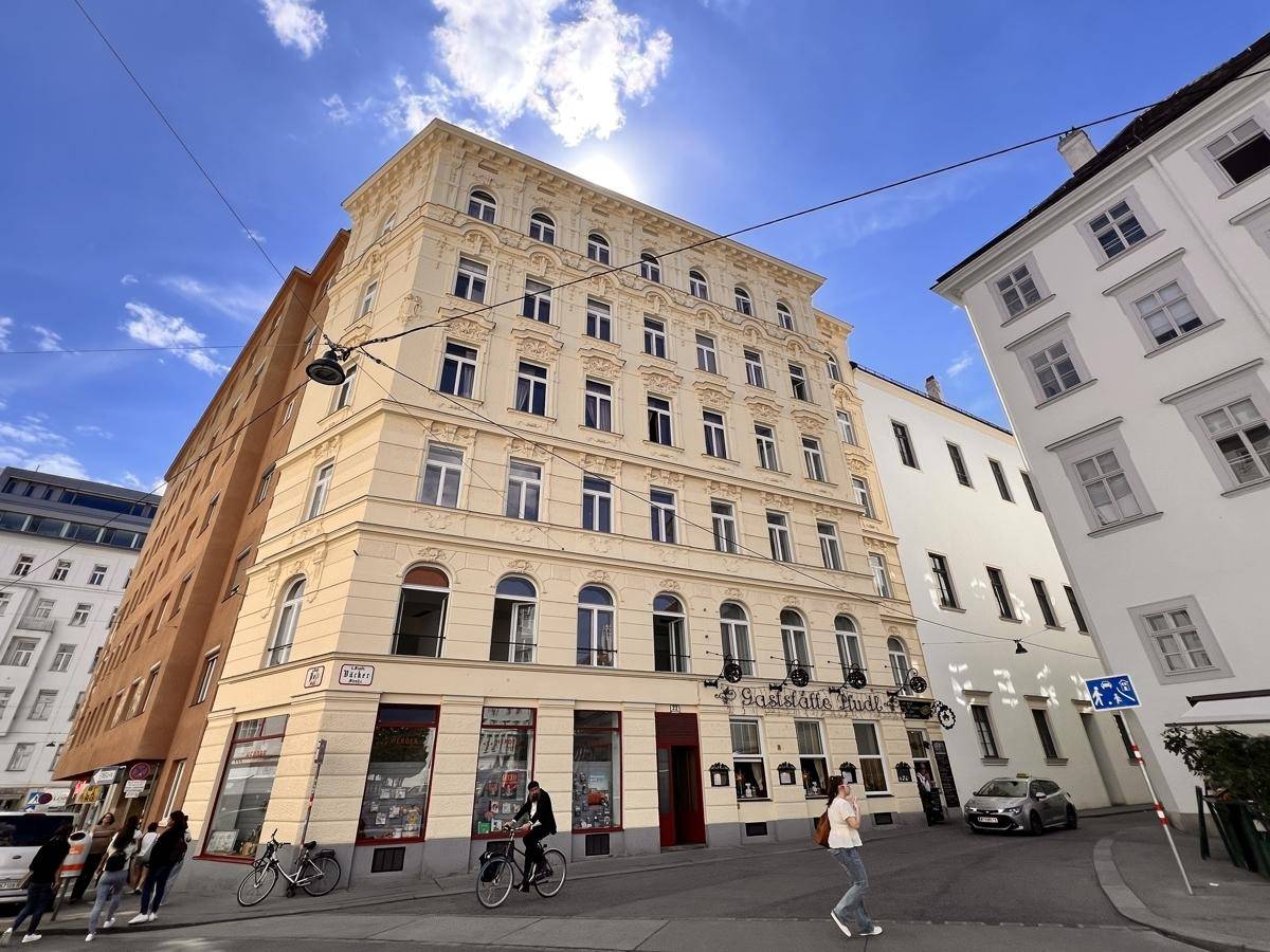 Eindrucksvolles Eckgebäude im historischen Stil mit vielen Fenstern und Geschäften im Erdgeschoss.