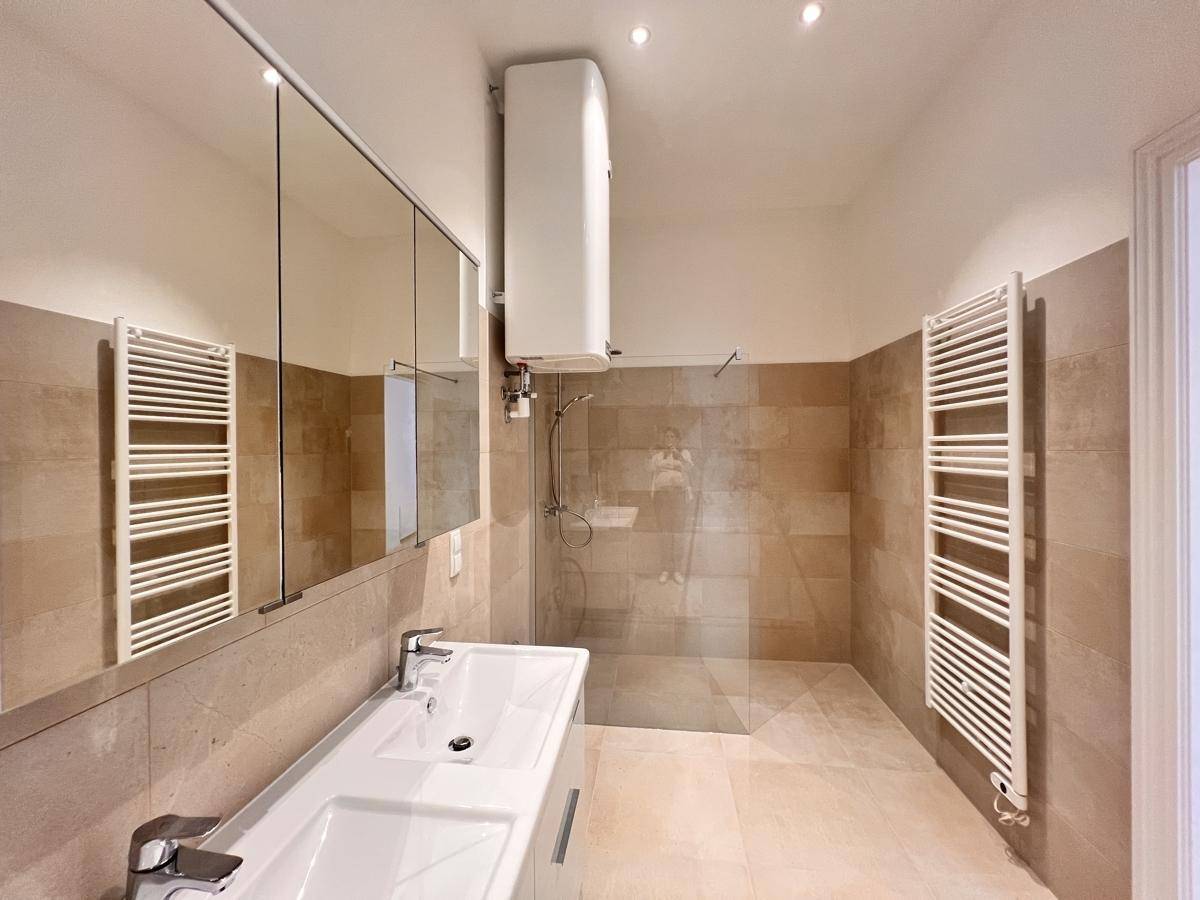 Modernes Badezimmer mit ebenerdiger Dusche, Einzelwaschbecken und beheizten Handtuchhaltern.