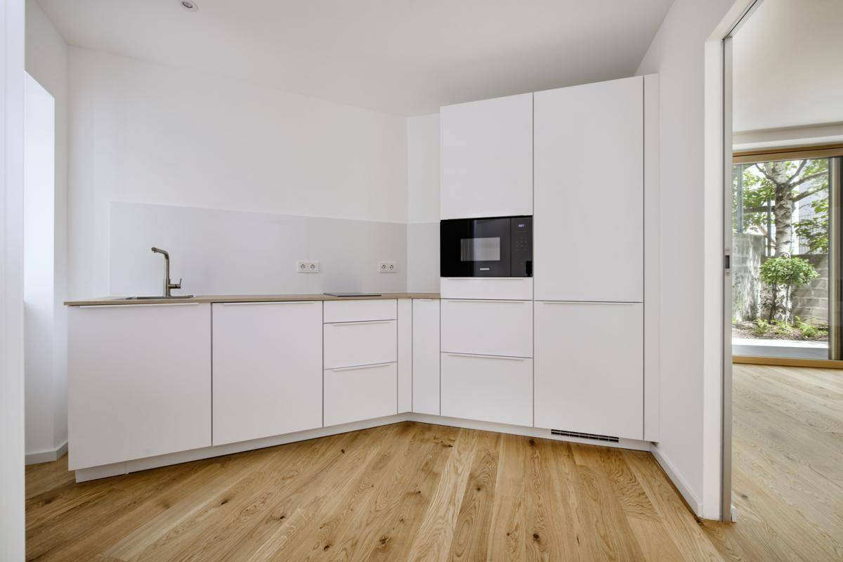 Eine moderne, weiße Einbauküche mit Holz-Arbeitsplatte und integriertem Backofen.