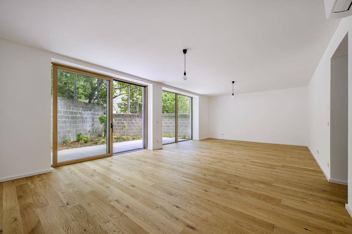 Ein geräumiges Wohnzimmer mit hellem Holzboden und großen Schiebetüren zur Terrasse.