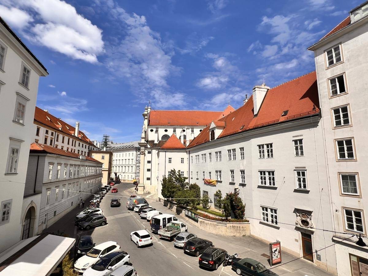Panoramablick auf eine historische Straße mit geparkten Autos und beeindruckender Architektur.