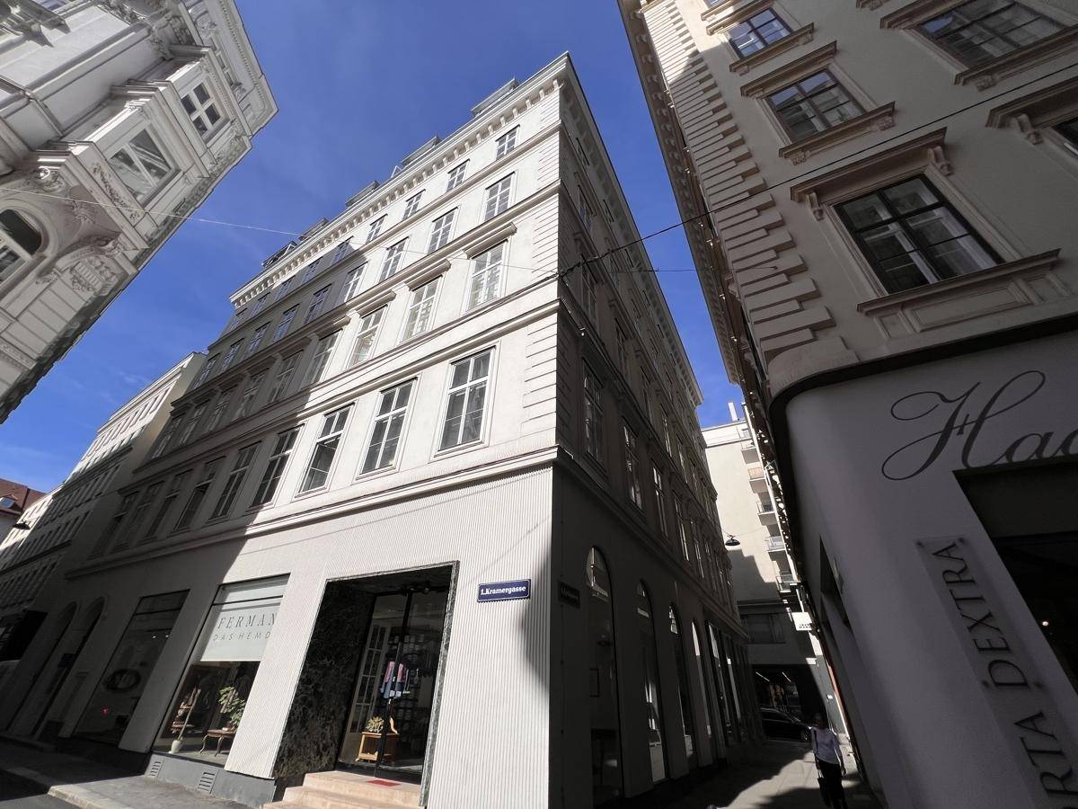 Historisches Gebäude in der Stadtansicht mit Geschäften im Erdgeschoss und vielen Fenstern.