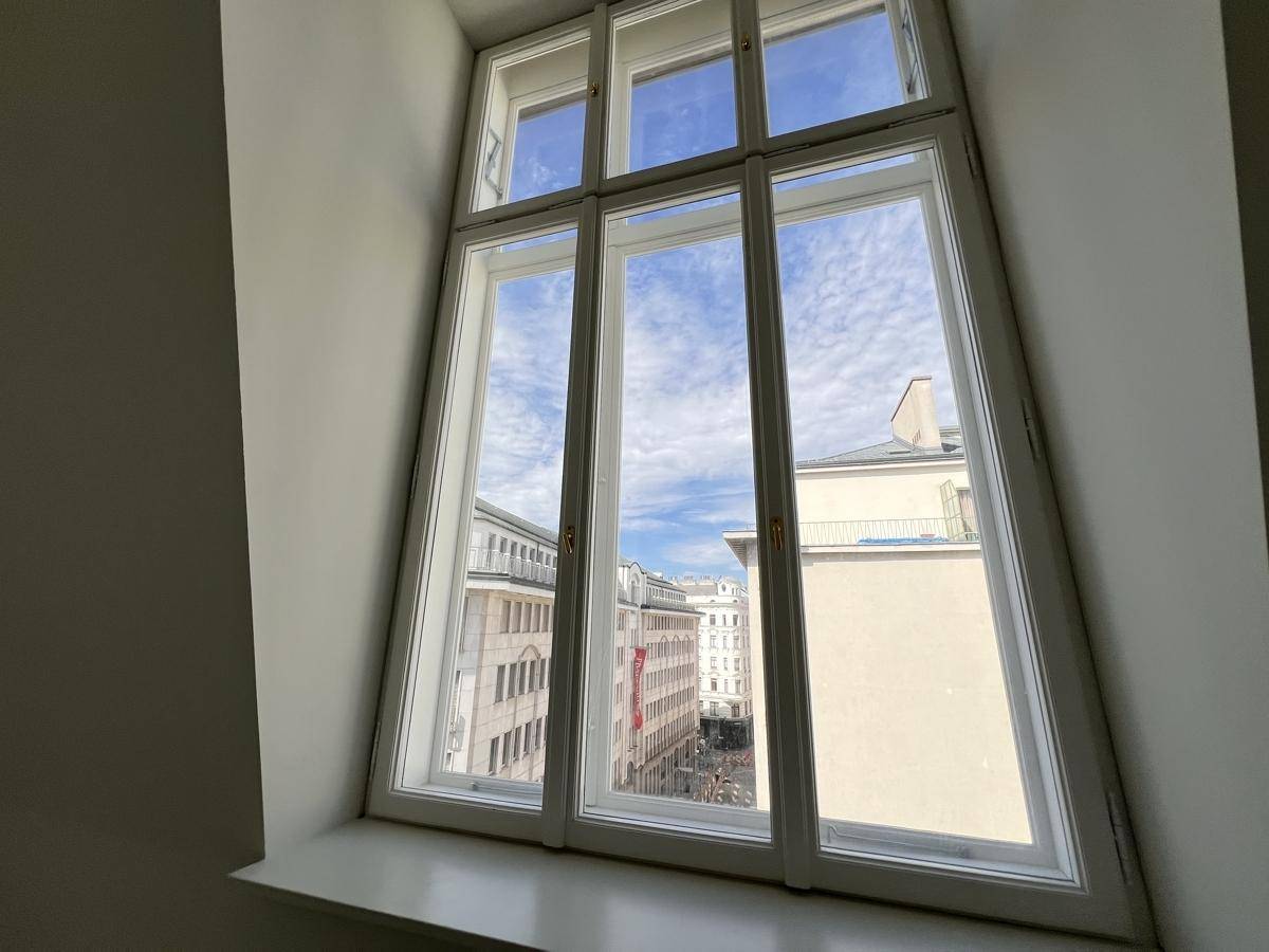 Großes Fenster mit Blick auf die umliegenden Gebäude und den blauen Himmel.