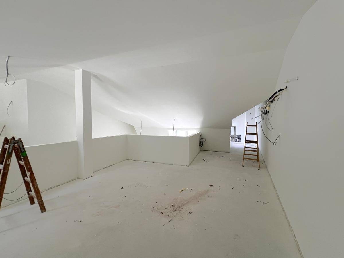 Geräumiger, unfertiger Innenraum mit hohen Decken und sichtbaren Kabeln, bereit für den weiteren Ausbau.