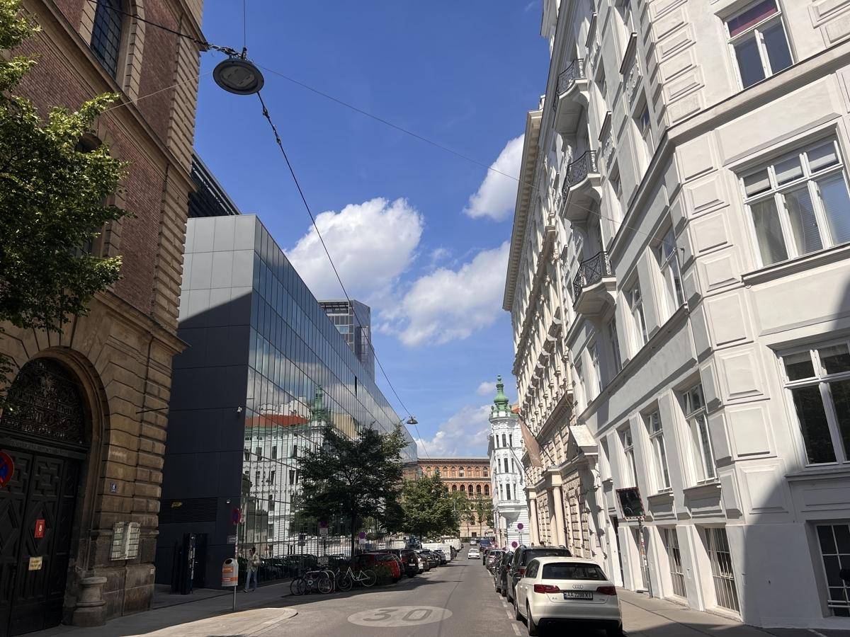 Blick auf eine belebte Straße mit historischen und modernen Gebäuden unter klarem Himmel.