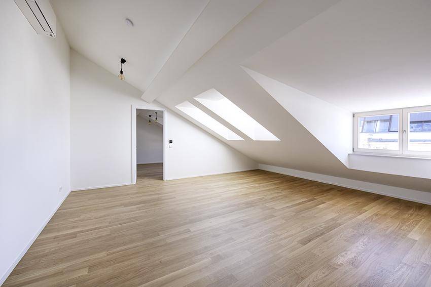 Helles Zimmer mit Dachschrägen, Oberlichtern und Parkettboden, ideal als Schlafzimmer.