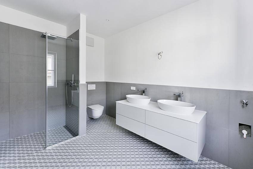 Modernes Badezimmer mit Doppelwaschbecken, wandhängendem WC und begehbarer Dusche.