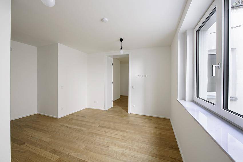Geräumiger, heller Raum mit großen Fenstern und hochwertigem Holzparkettboden.