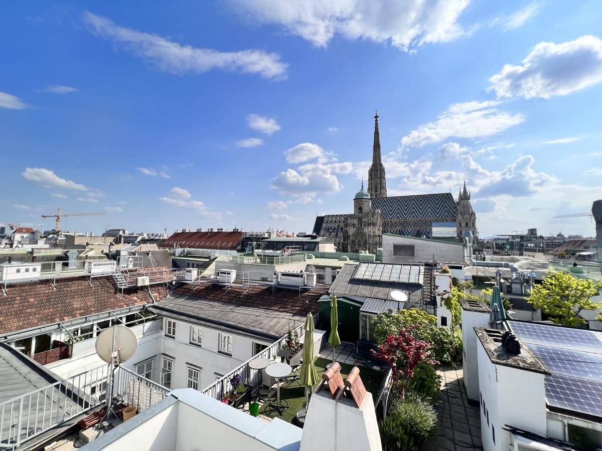 Panoramablick über die Dächer Wiens mit dem Stephansdom unter blauem Himmel.
