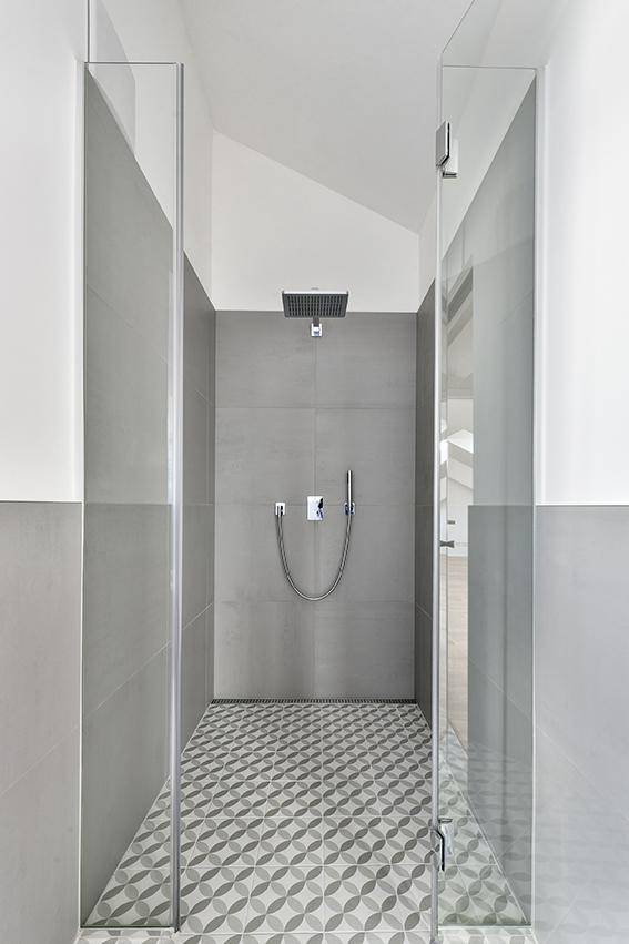 Moderne begehbare Dusche mit Regenduschkopf und stilvollen Bodenfliesen.