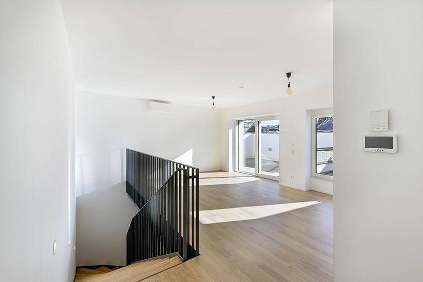 Heller Wohnbereich mit Holzparkett, Balkonzugang und moderner Treppe.