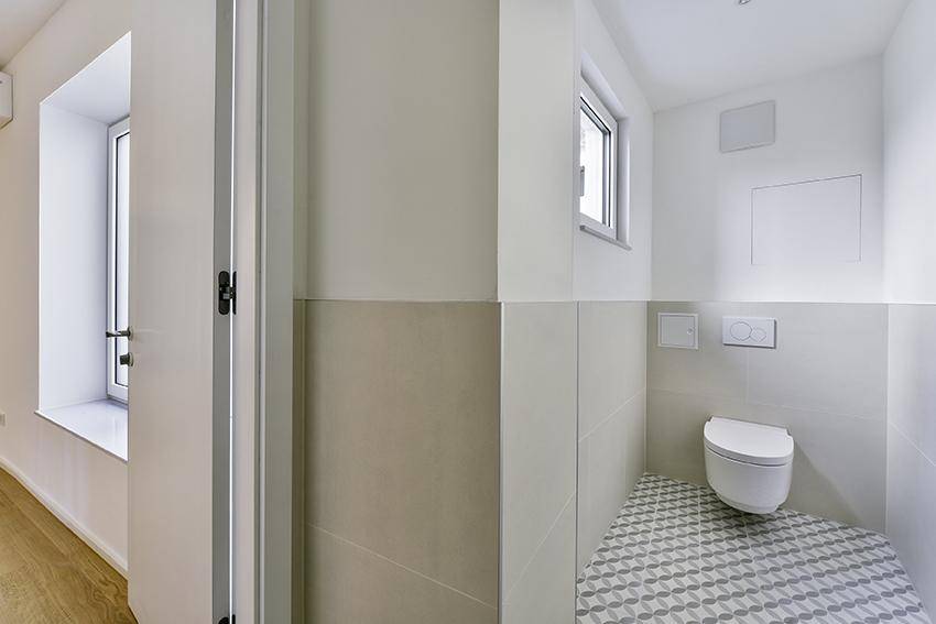 Helles Interieur mit Fenster und modernem Gäste-WC mit gemusterten Fliesen.