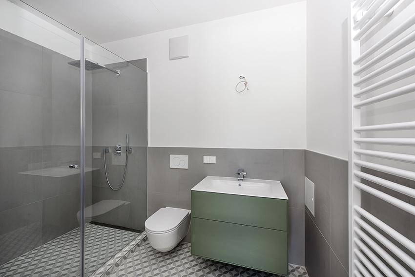 Modernes Badezimmer mit begehbarer Dusche, WC, Waschtisch und Handtuchheizkörper.