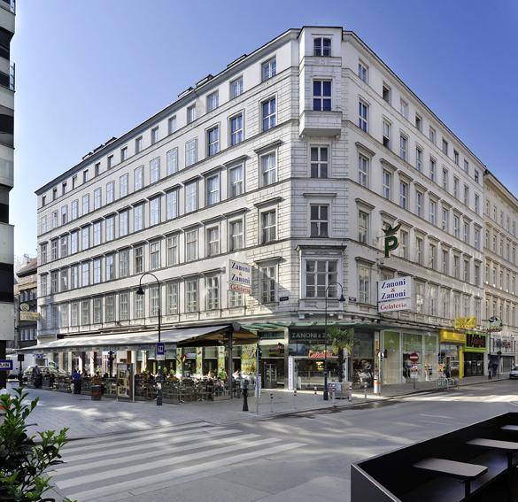 Historisches Gebäude an einer Straßenecke mit Geschäften und Restaurants im Erdgeschoss.