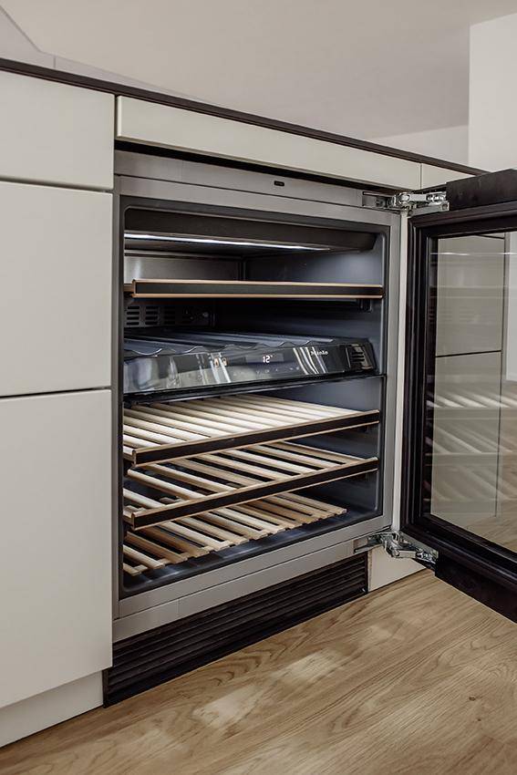 Integrierter Weinkühlschrank mit Holzregalen in einer modernen Küche.