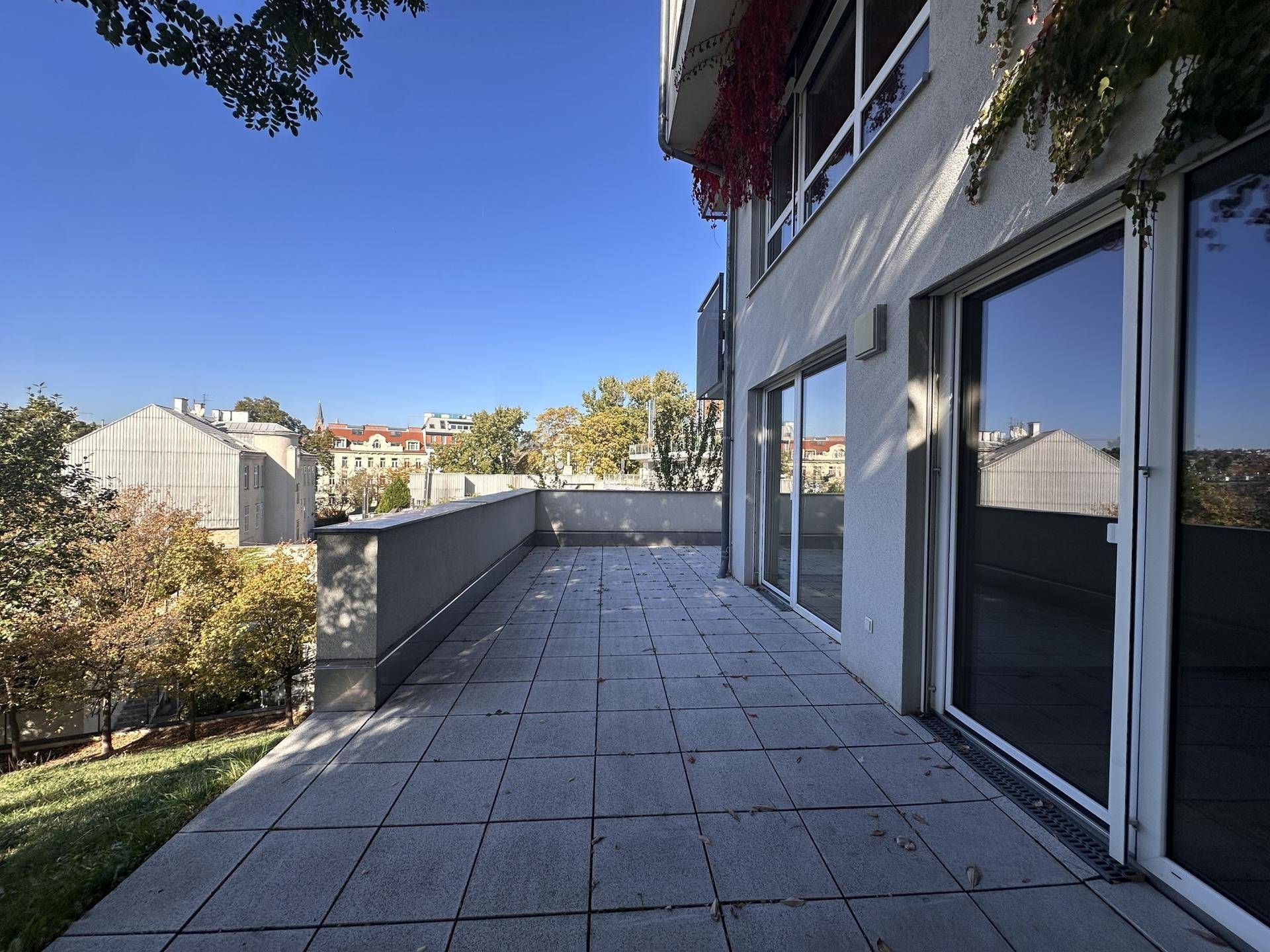 Weitläufige Terrasse mit Fliesenboden und Panoramablick auf die grüne Umgebung.