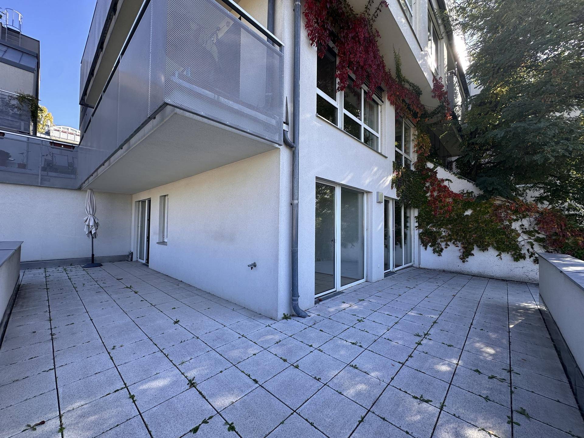 Große, leere Terrasse mit Fliesenboden und Blick auf die umliegende Bebauung.