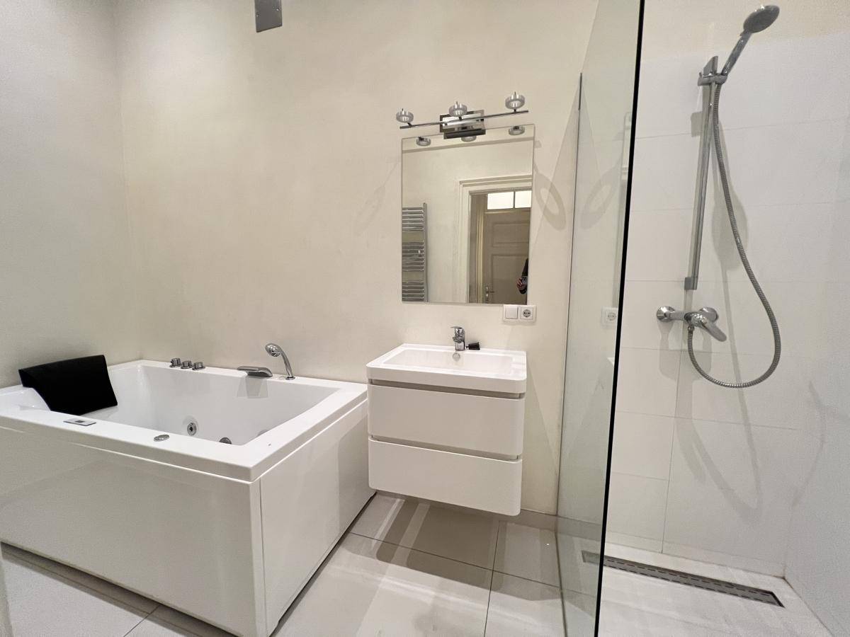 Modernes Badezimmer mit Whirlpool-Badewanne, Einzelwaschbecken und begehbarer Dusche.