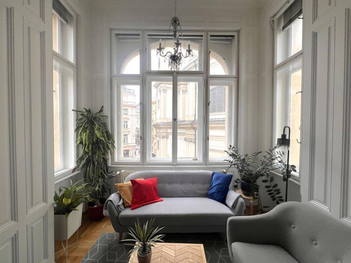 Helles Wohnzimmer mit hohen Decken, großen Fenstern und stilvollen Möbeln, sehr einladend.