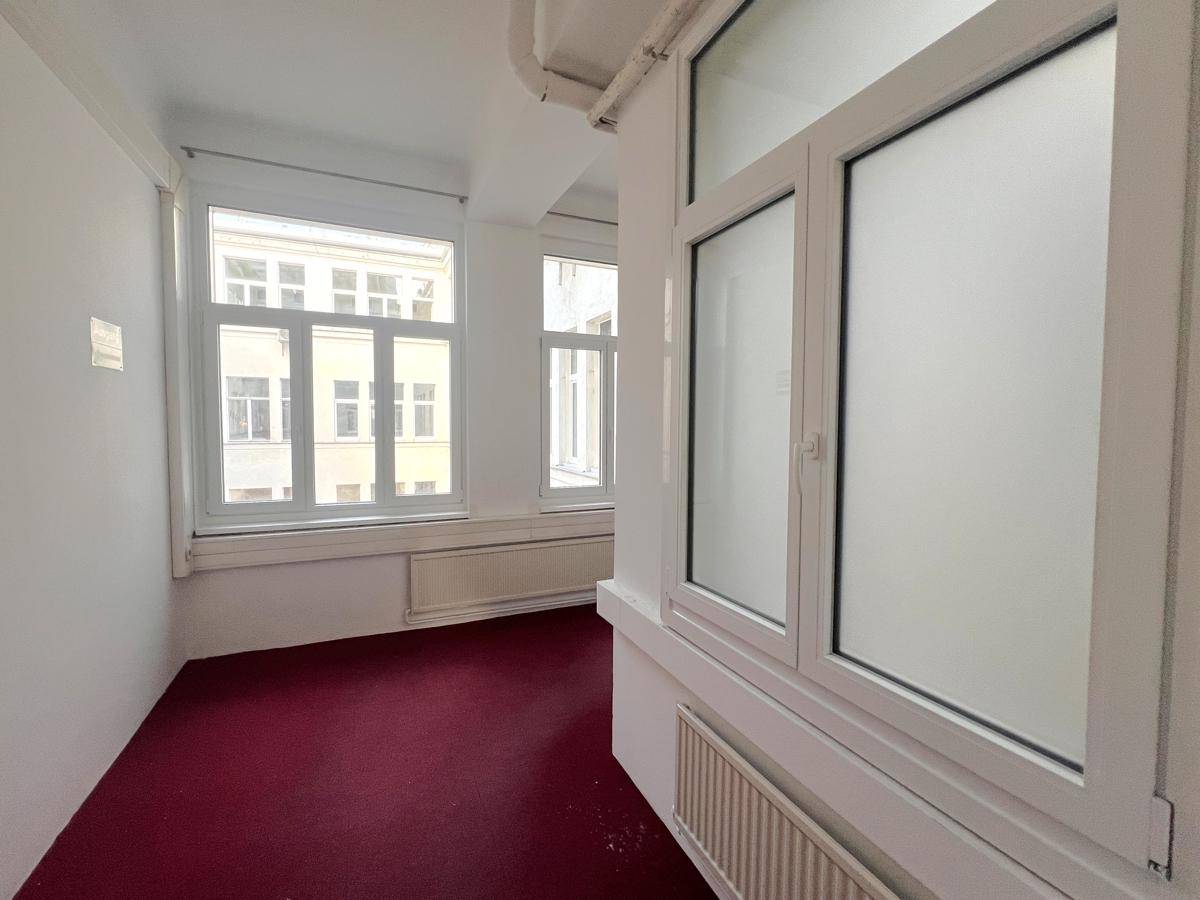 Büro mit rotem Teppichboden und mehreren Fenstern, teilweise mit Milchglas, für Privatsphäre und Licht.