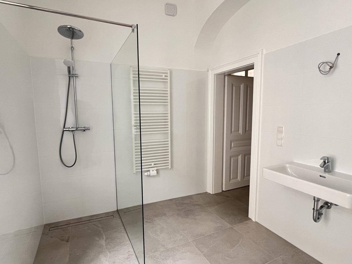 Modernes Badezimmer mit ebenerdiger Dusche, Einzelwaschbecken und beheiztem Handtuchhalter.