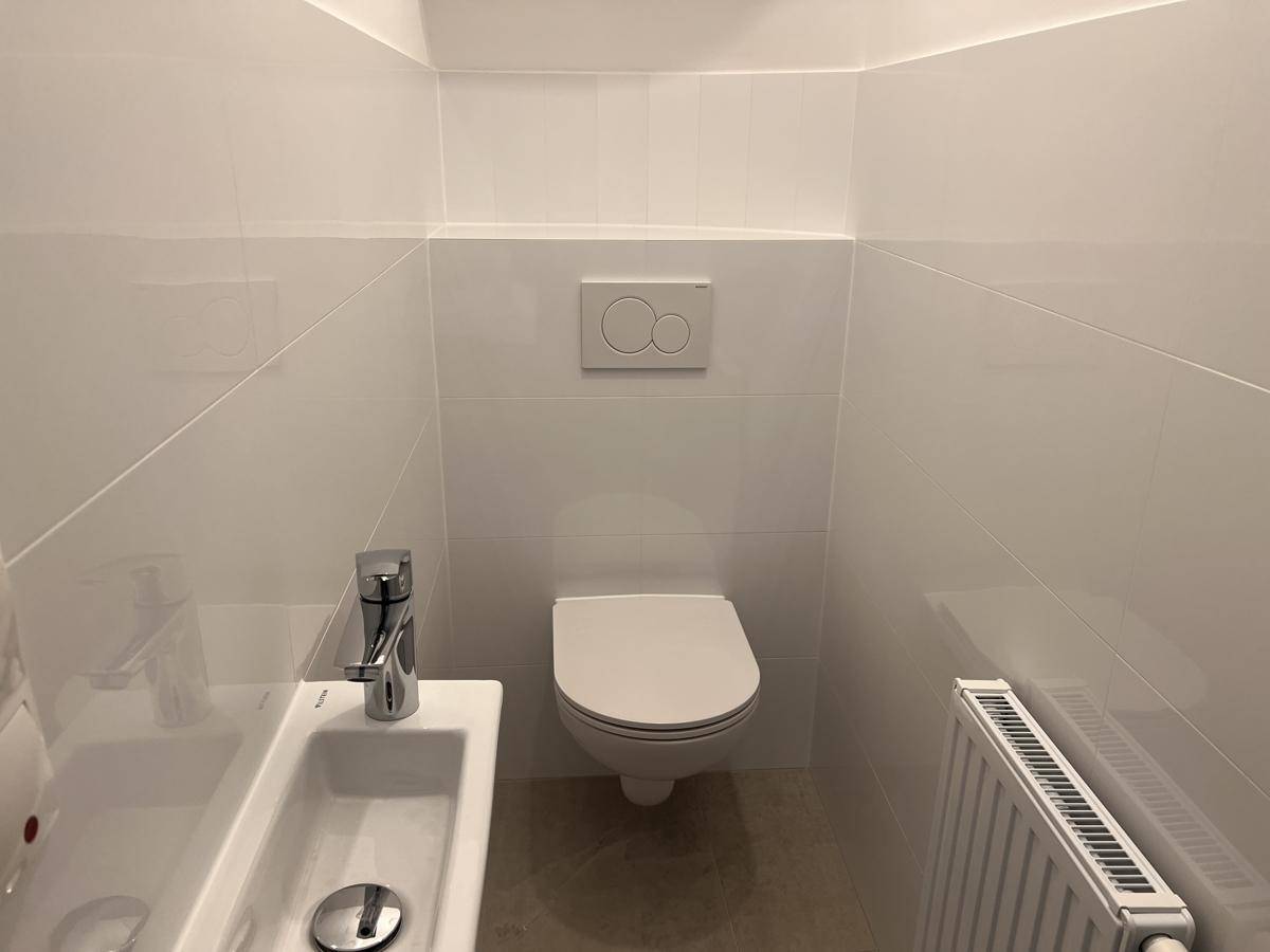 Modernes Gäste-WC mit wandhängender Toilette und kleinem Waschbecken.