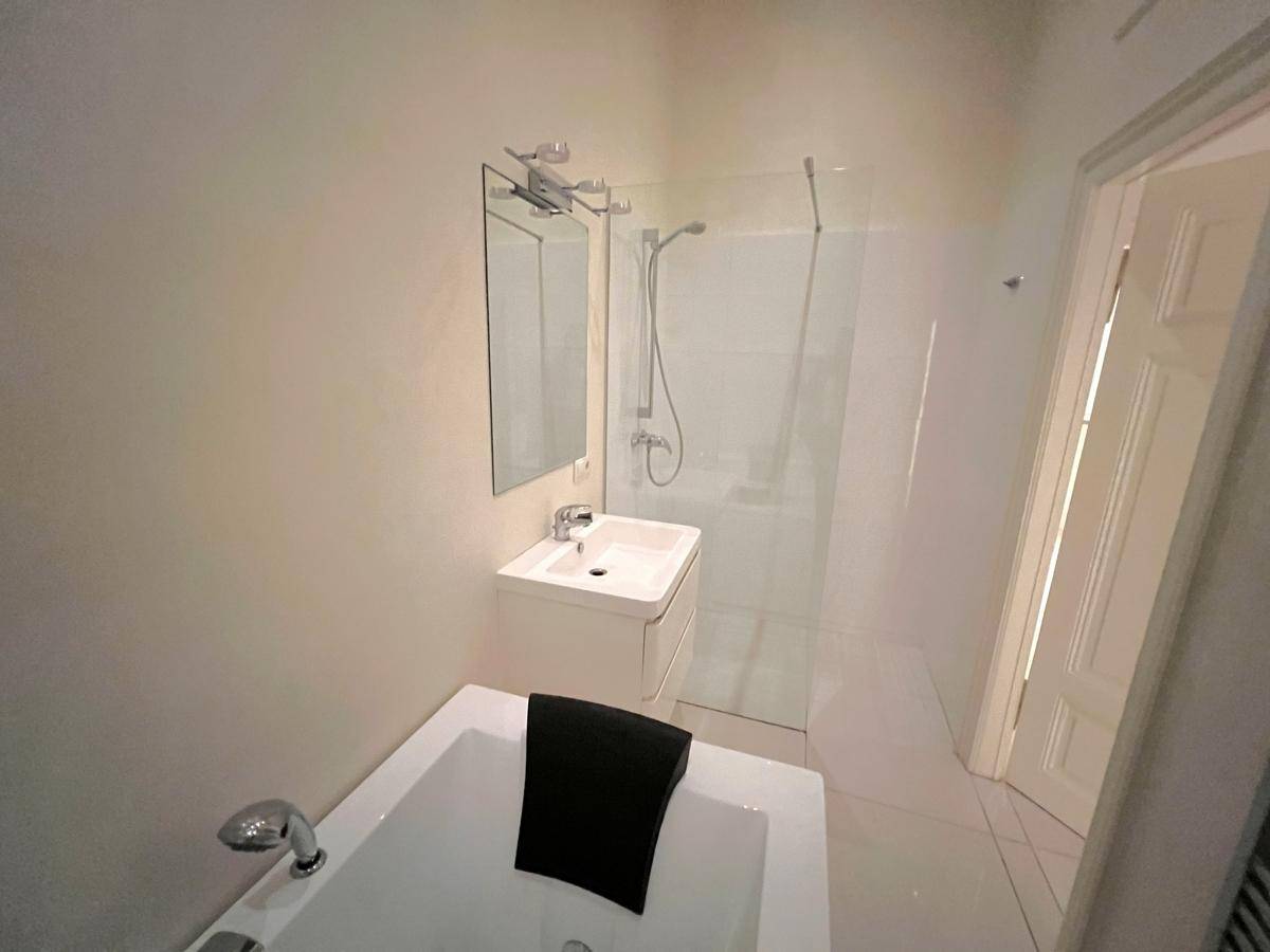 Helles Badezimmer mit moderner Dusche, Badewanne und einem Waschbecken mit Spiegelschrank.