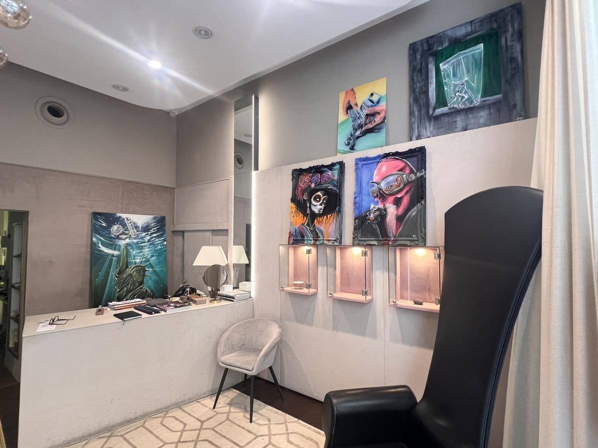 Eleganter Verkaufsraum mit Kunstwerken, beleuchteten Vitrinen und einem stilvollen Sessel.