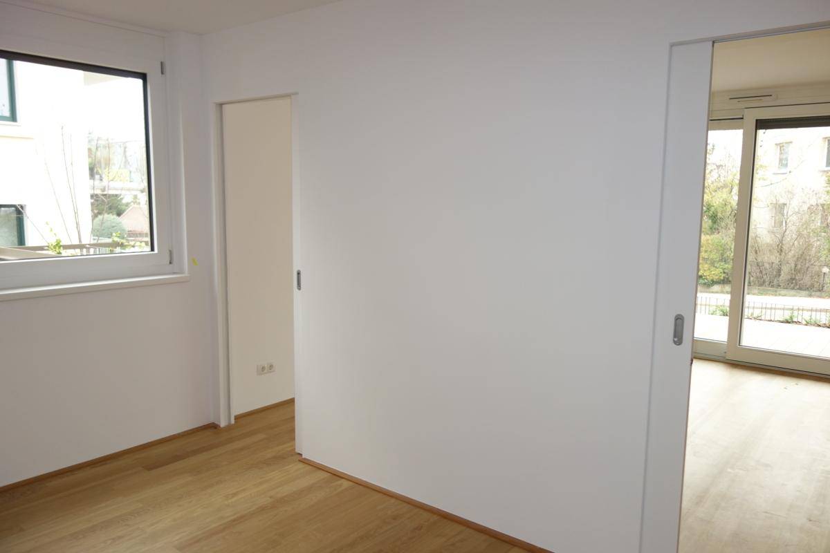 Heller Innenraum mit Parkettboden und Schiebetüren, der verschiedene Bereiche verbindet.