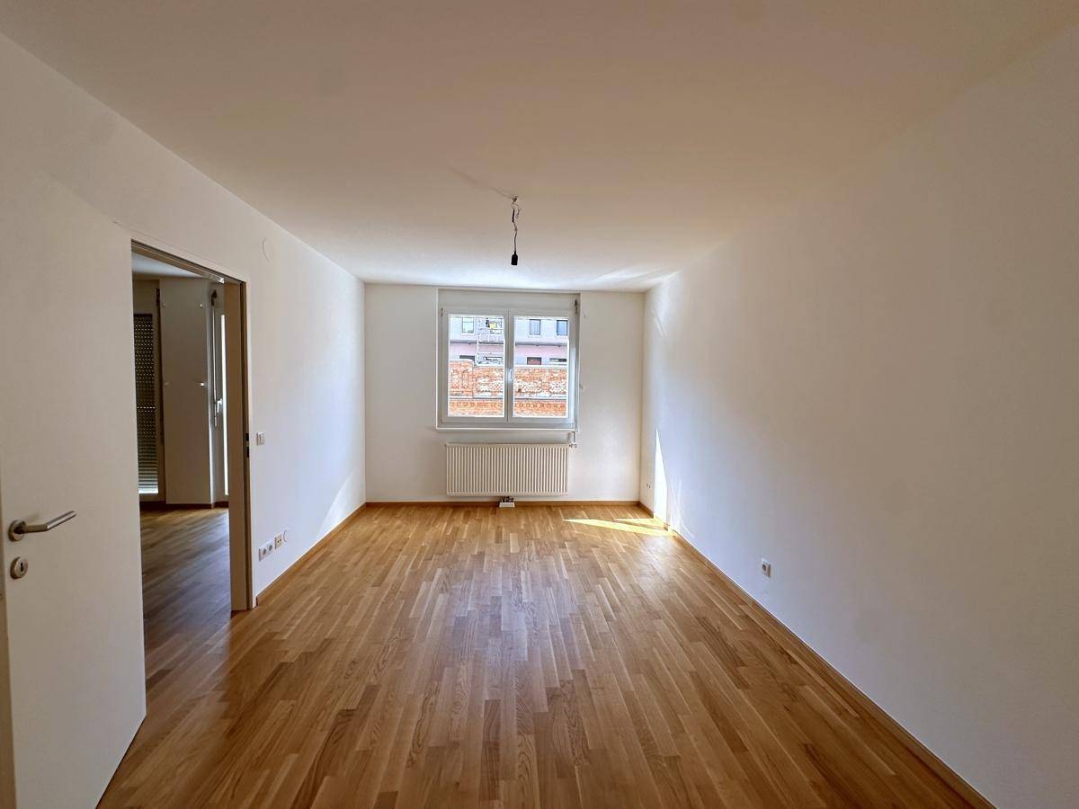 Heller, unmöblierter Raum mit Parkettboden und Fenster, vielseitig nutzbar.