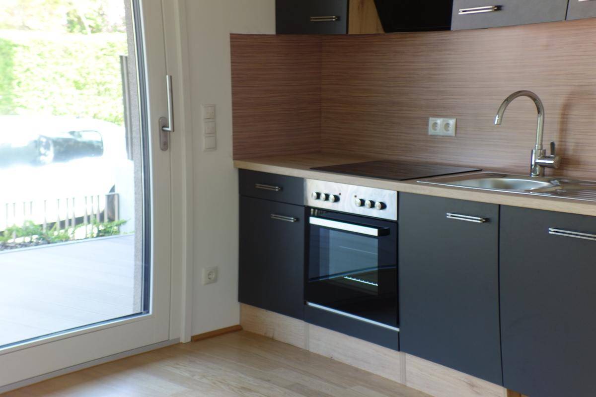 Moderne Einbauküche mit dunklen Schränken, Holz-Arbeitsplatte und integrierten Geräten.