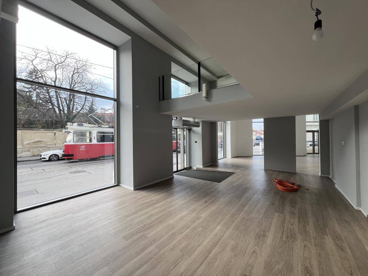 Heller Gewerberaum mit großen Fenstern zur Straße und modernem Laminatboden, bereit zur individuellen Gestaltung.