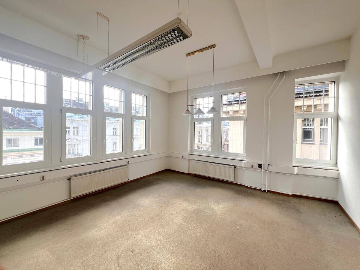 Großes, helles Büro mit vielen Fenstern, die einen weiten Blick bieten, und einem hellen Teppichboden.