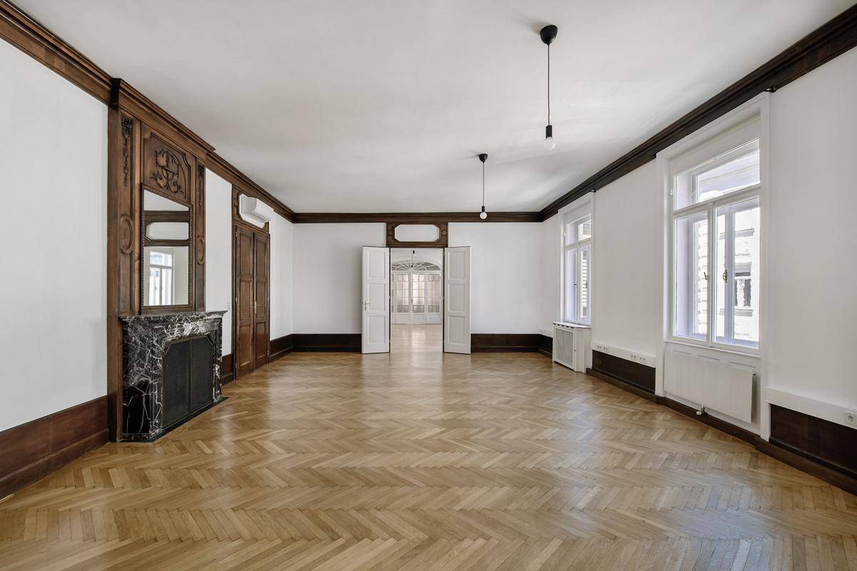 Großzügiges Wohnzimmer mit Fischgrätparkett, Holztäfelung und einem dekorativen Kamin.