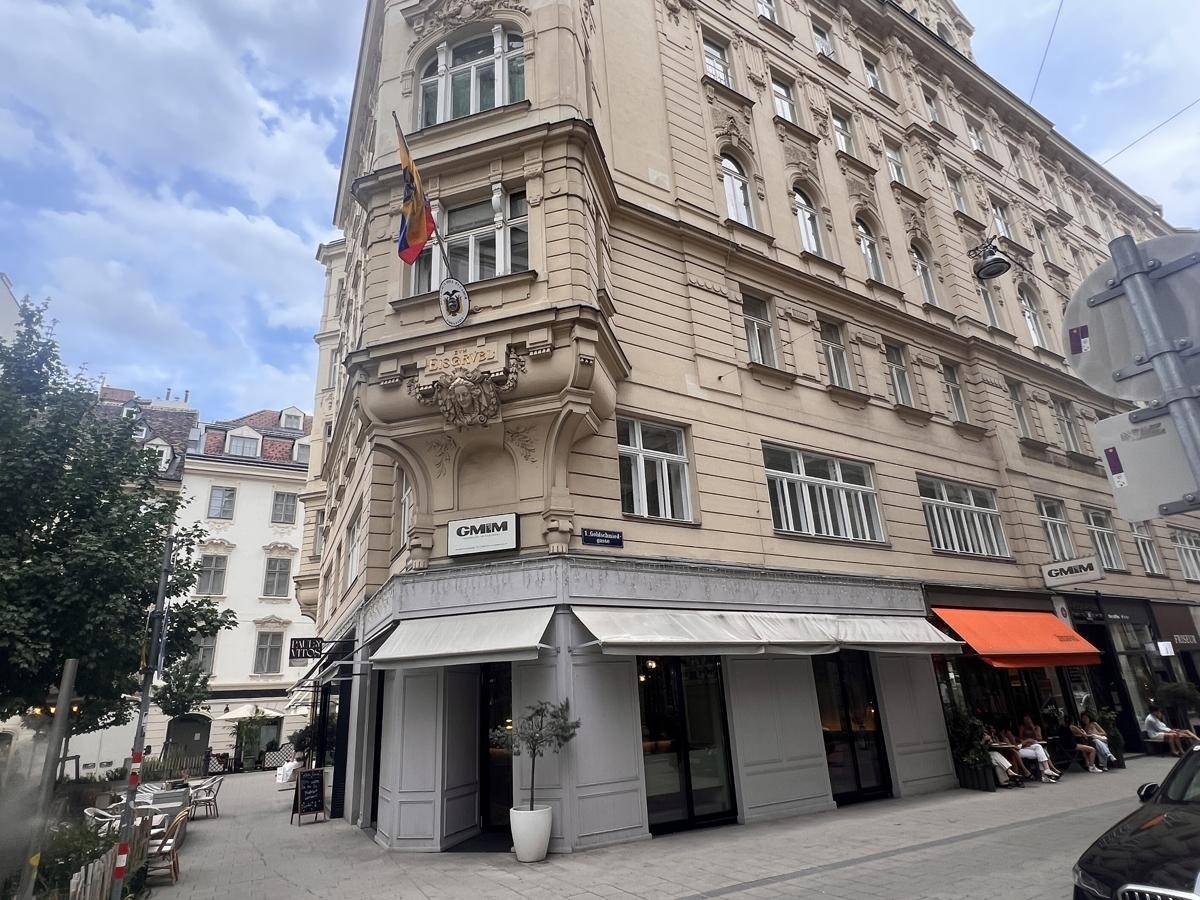 Elegantes Eckgebäude mit klassischer Architektur und Geschäften im Erdgeschoss, an einer Straße gelegen.