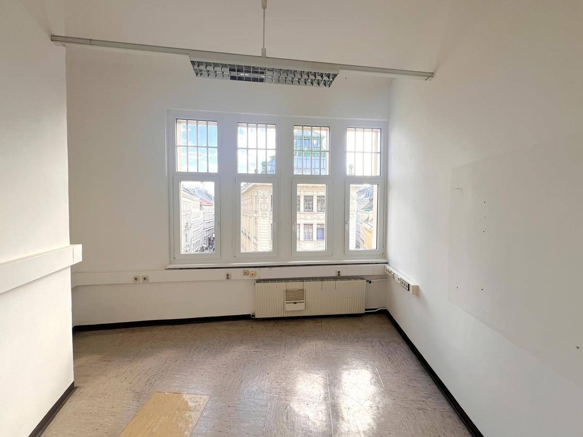 Helles Büro mit hellem Boden, weißen Wänden und einem großen Fenster, das den Raum gut belichtet.
