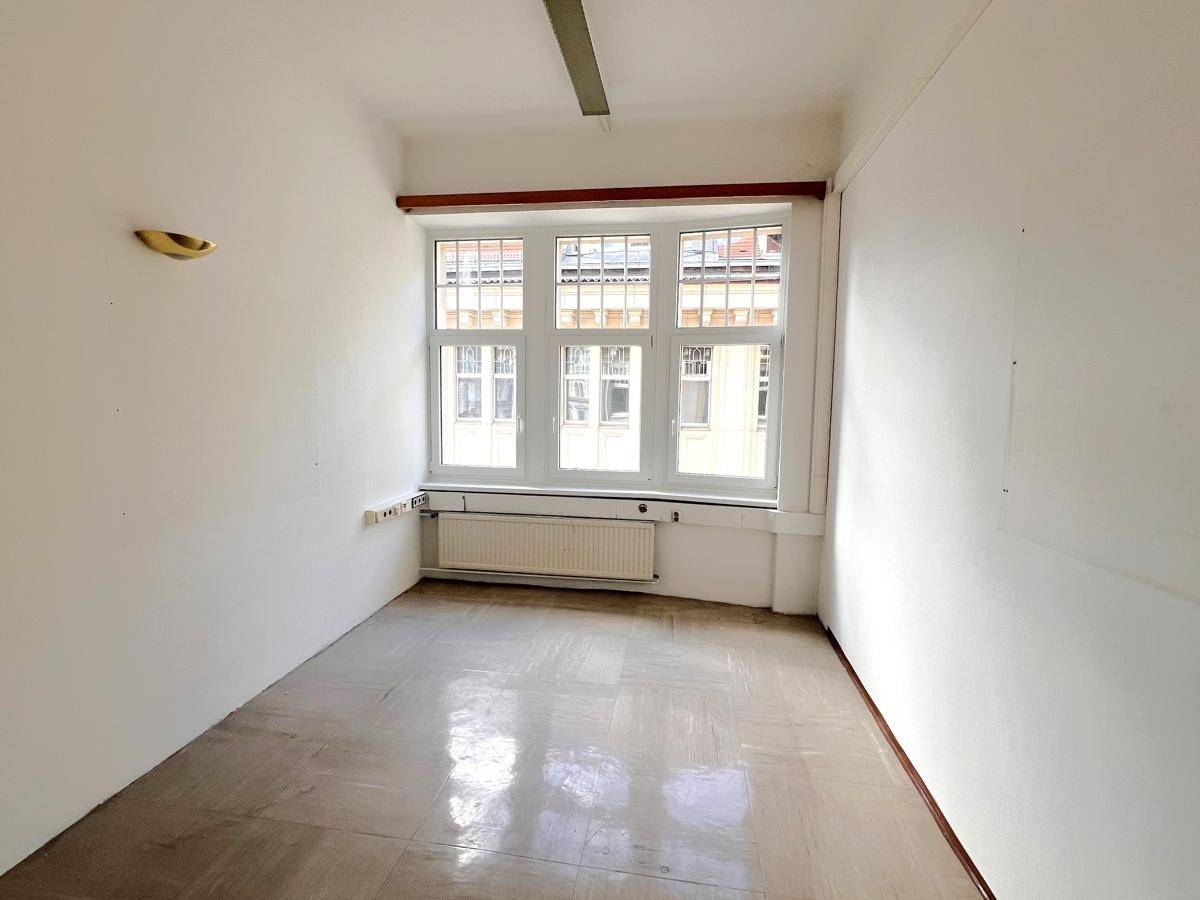 Kleineres Büro mit hellem Boden, weißen Wänden und einem großen Fenster, das viel Licht spendet.
