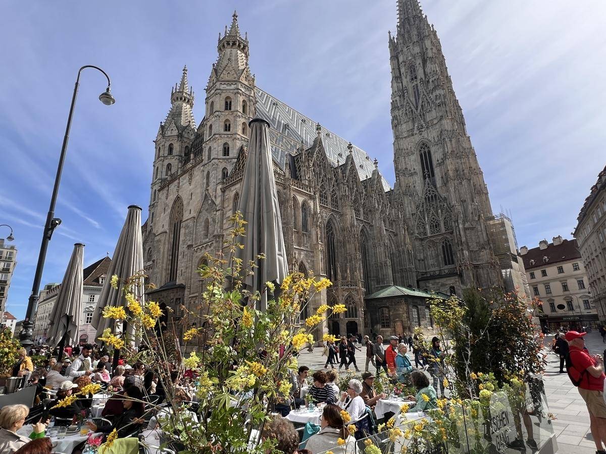 Der majestätische Stephansdom in Wien, umgeben von belebten Straßencafés und vielen Besuchern.