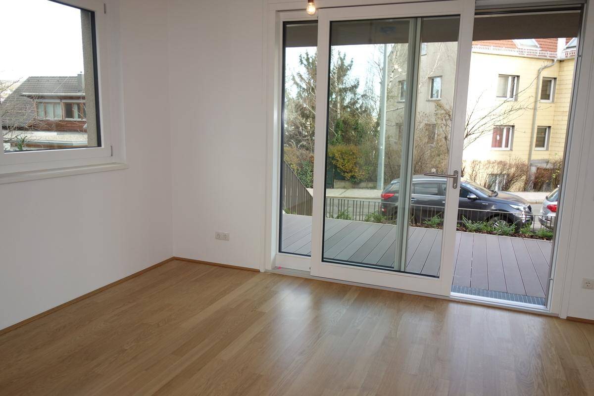 Lichtdurchfluteter Wohnbereich mit Parkettboden und großzügigem Zugang zur Außenterrasse.
