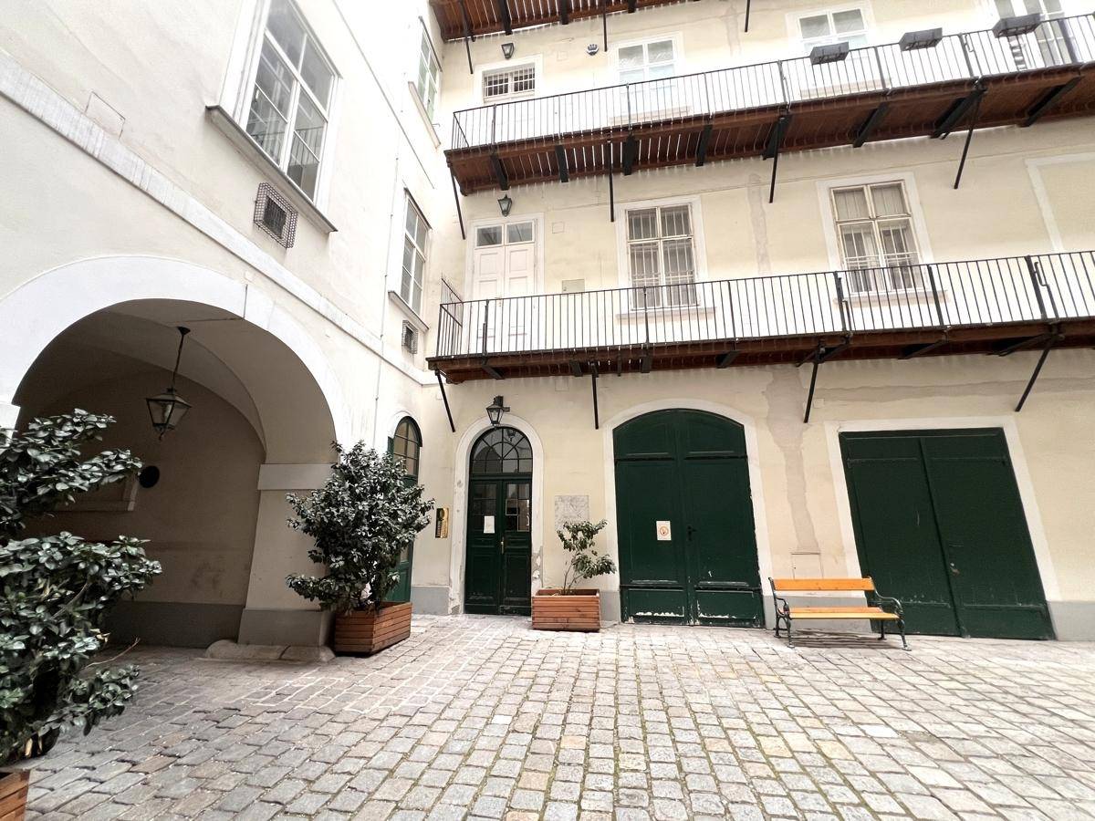 Historischer Innenhof mit Kopfsteinpflaster, Pflanzen und traditioneller Architektur.